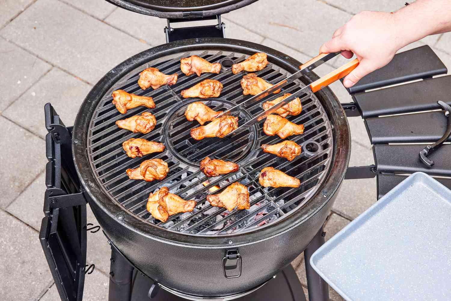 A person removes chicken from the Char-Griller E16620 Akorn Kamado Charcoal Grill