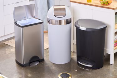 Three kitchen trashcans in a kitchen. 