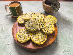 Wooden platter of egg bites, with one cut open. On a stone surface, with coffee and a small plant in the background