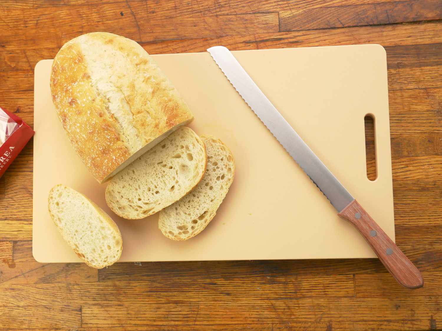 an overhead shot of the yoshihiro cutting board with a bread knife and sliced bread