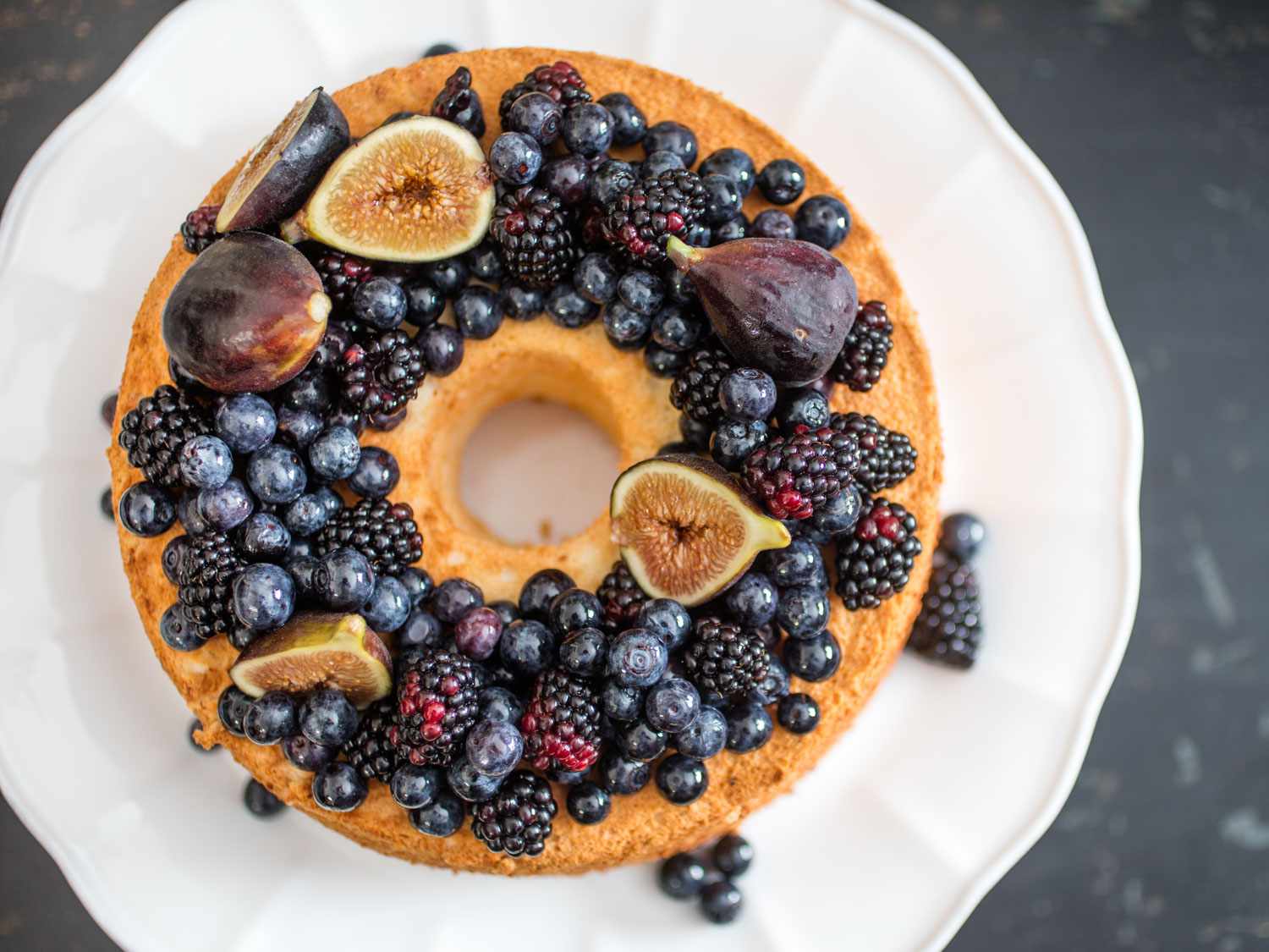 Overhead view of angel food cake with fresh figs, blackberries, and blueberries arranged on top.