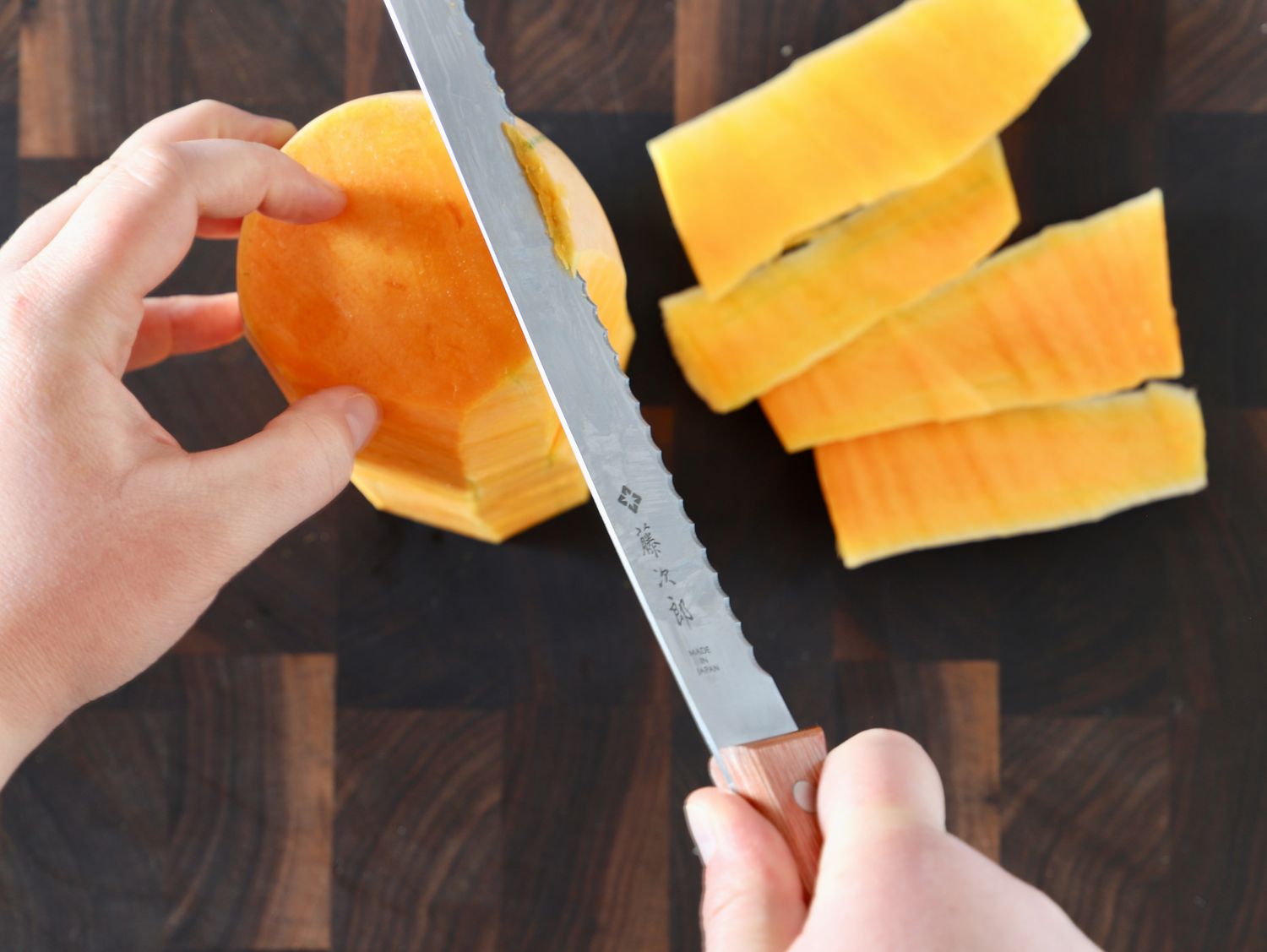 A person using a bread knife to peel butternut squash