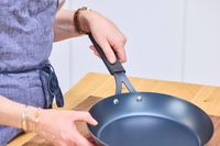 A person examines the OXO Obsidian 10 Inch Pre-Seasoned Carbon Steel Frying Pan