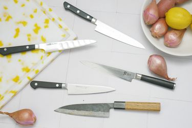 five petty knives on a white tile surface