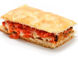 A fried-eggplant sandwich with eggplant mayo, set on a white surface.