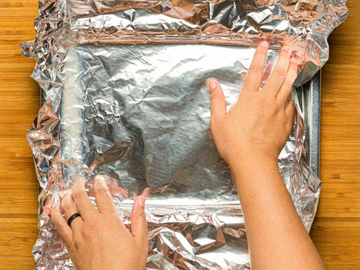 Overhead view of lining a pan with aluminum foil
