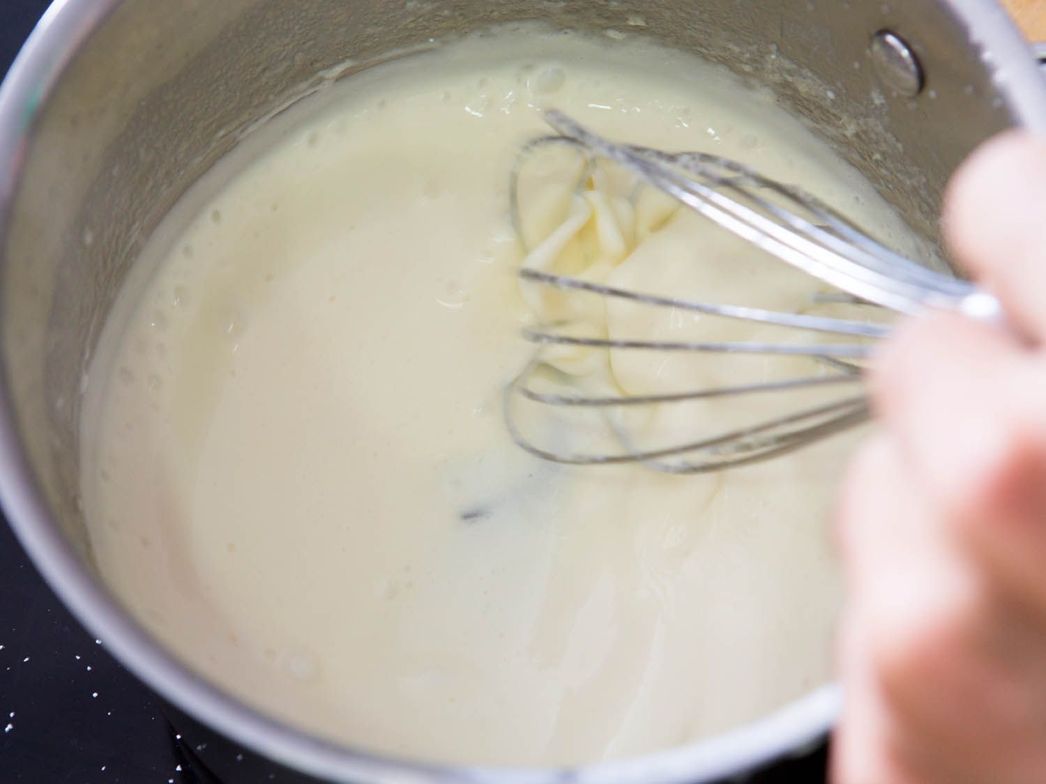 Whisking Parmesan cheese in a cream sauce.