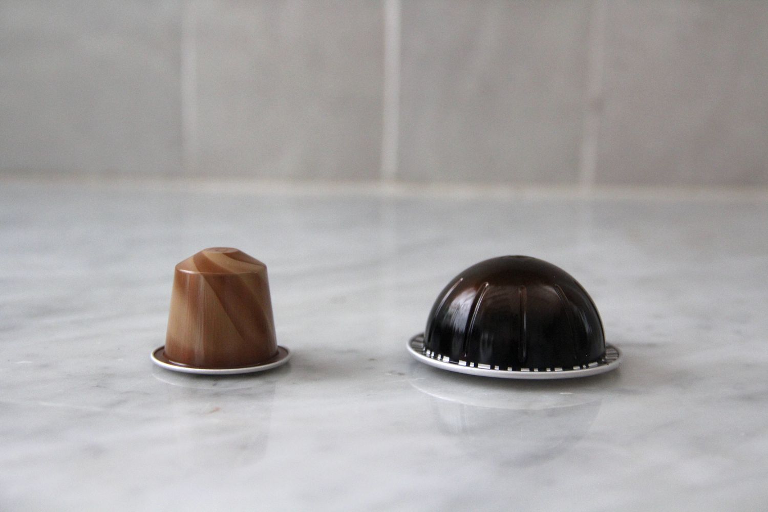 Two Nespresso Scuro pods on a marble countertop.