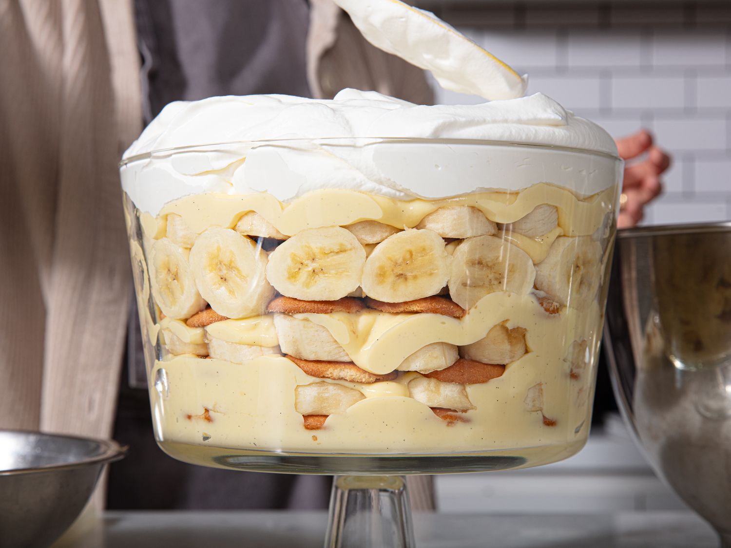 Side view of banana pudding being topped iwht whipped cream