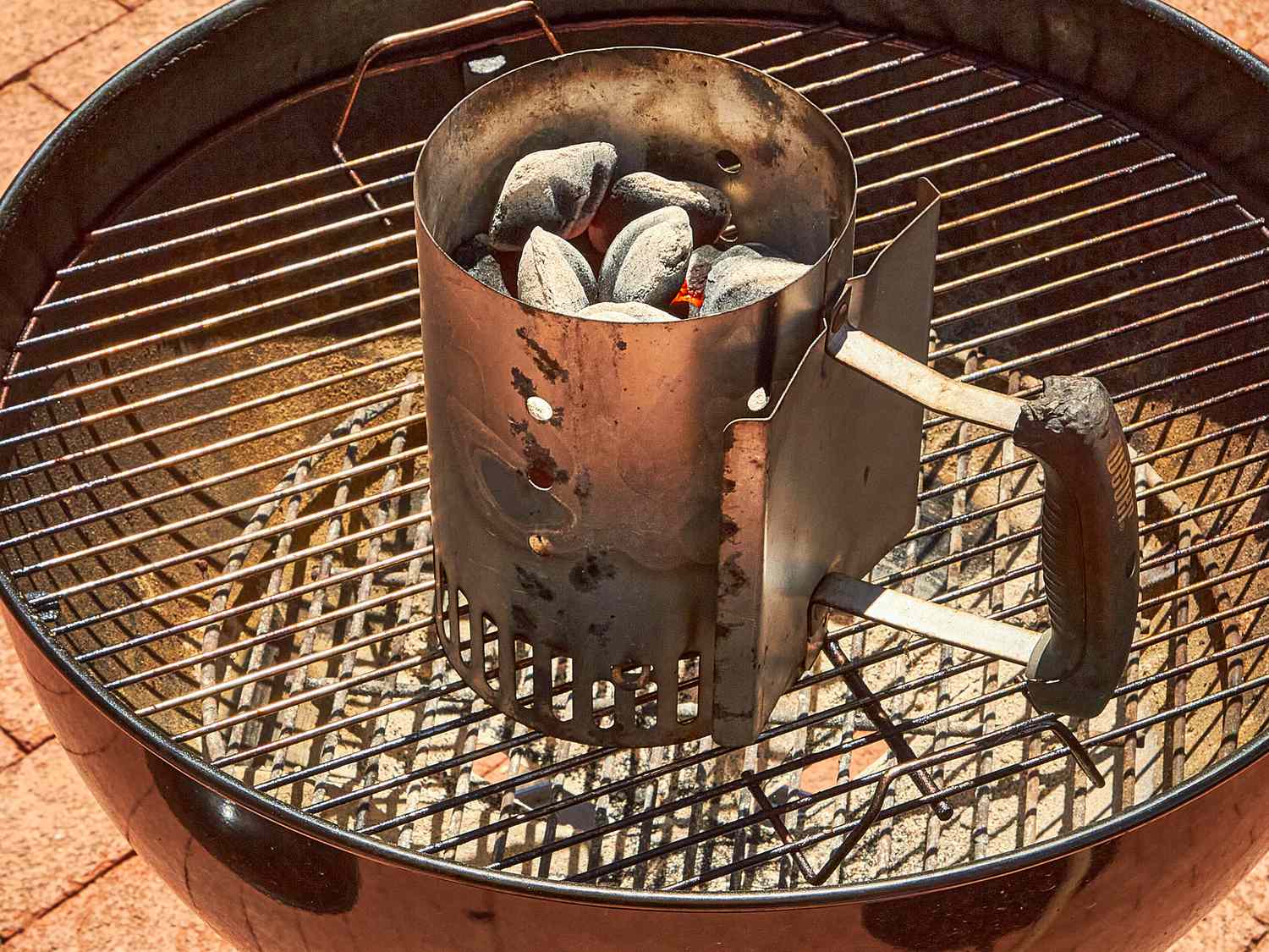 Charcoal starter with lit coals placed on a barbecue grill