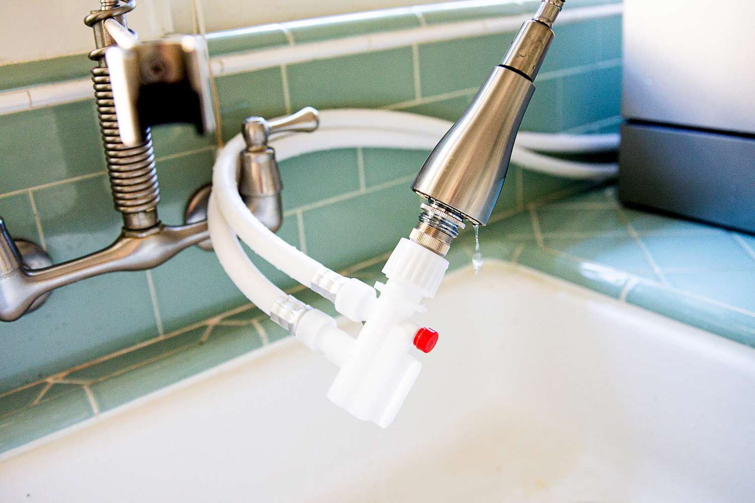 A faucet connected to a countertop dishwasher.