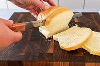 Person slicing bread with Tojiro F-737 Bread Slicer