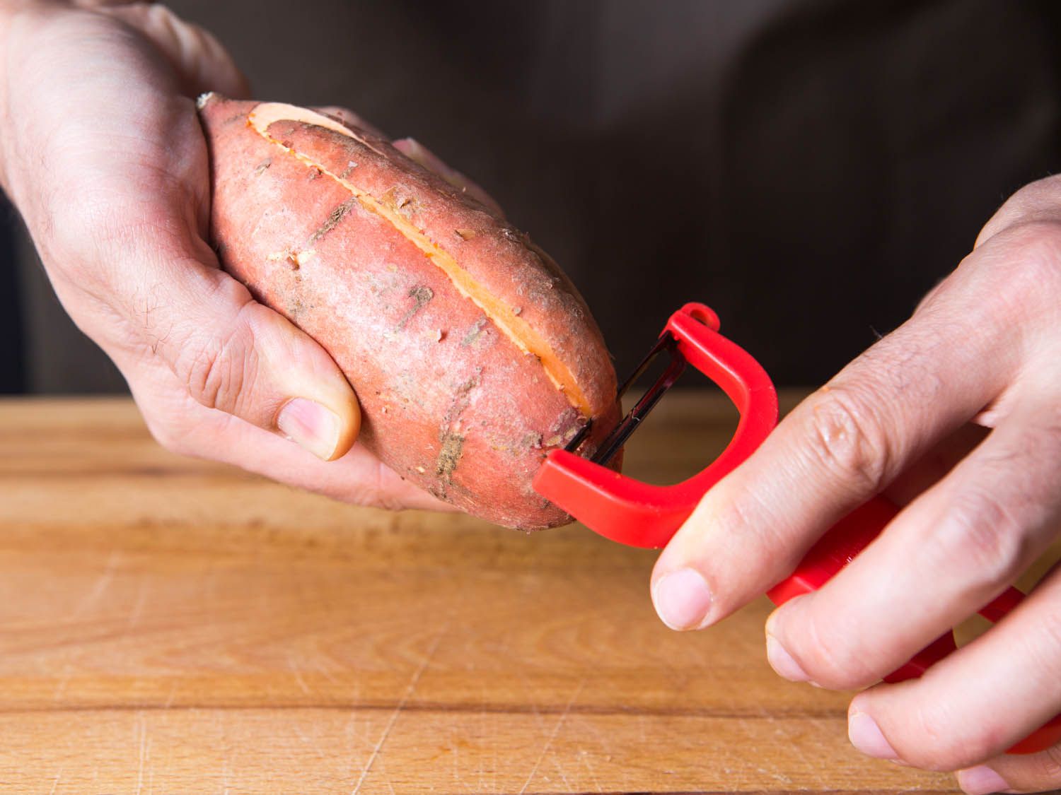 A y-peeler peeling a sweet potato