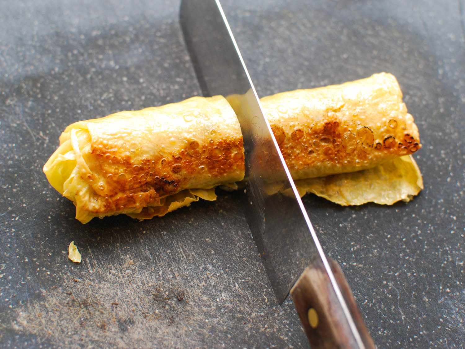 The browned rolls are cut in half with a knife.