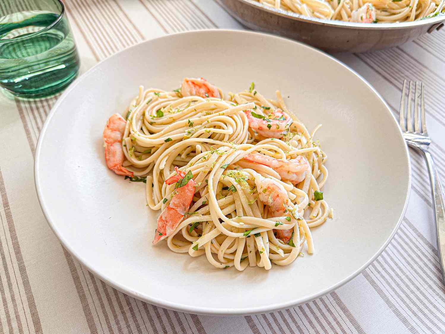 A dish of shrimp pasta served on a plate with garnish