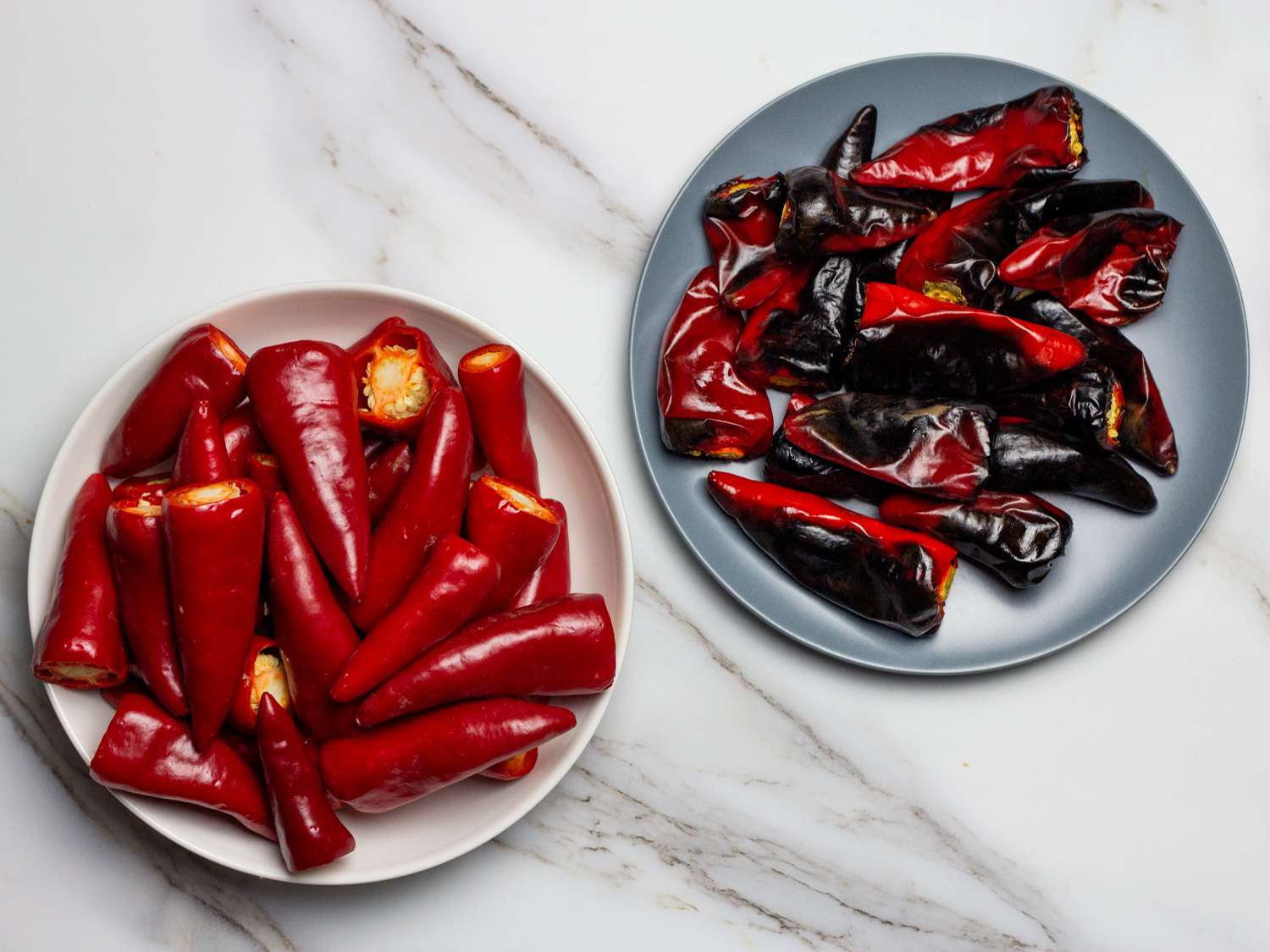 Overhead of fresh and roasted chile peppers side by side on plates.