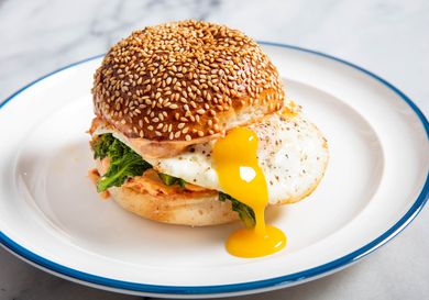 a Fried Egg Sandwiches With 'Nduja Mayo and Broccoli Rabe on a seeded hamburger bun, the yolk dripping down the side