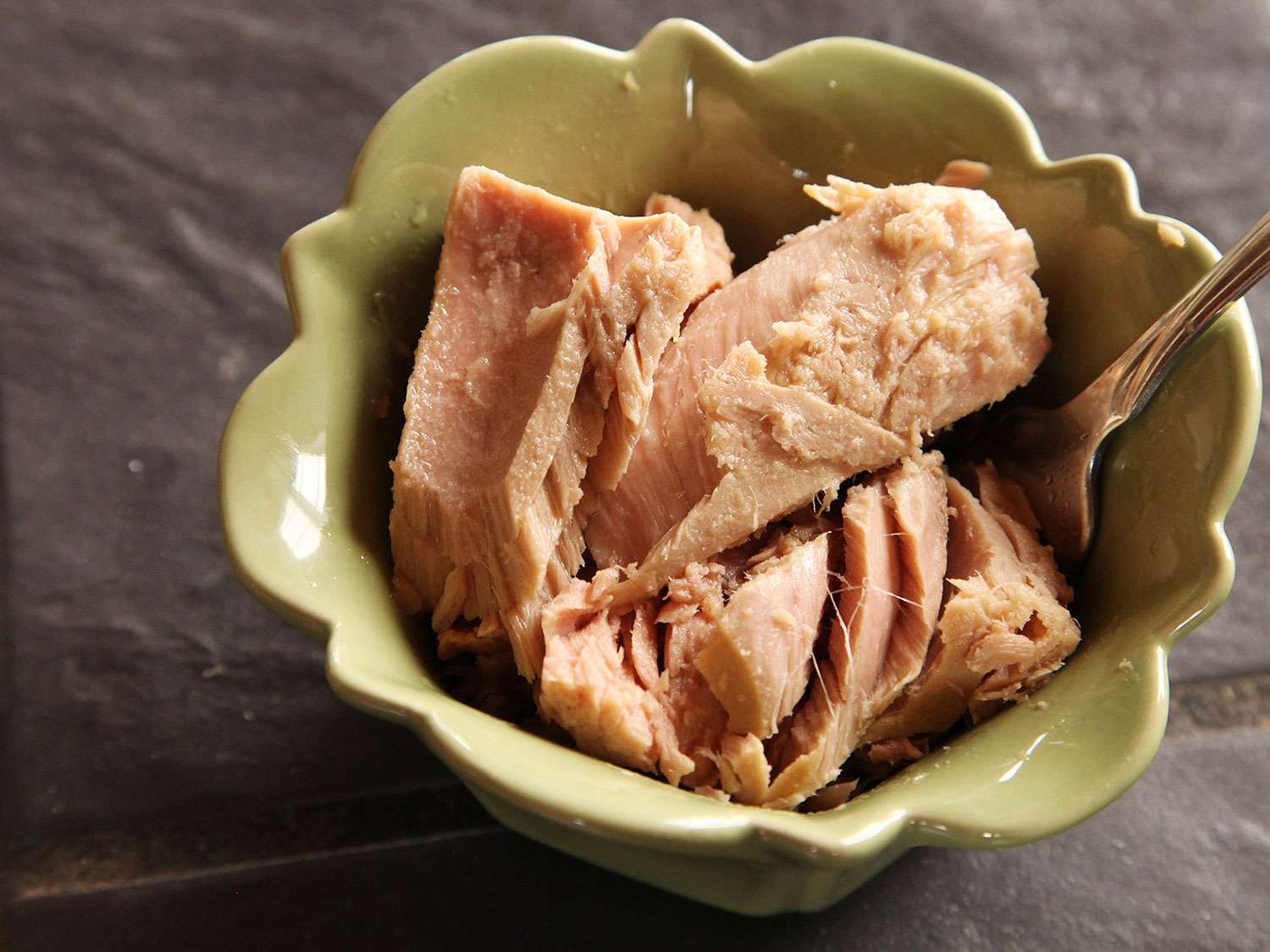 Drained canned tuna in a bowl with a fork.