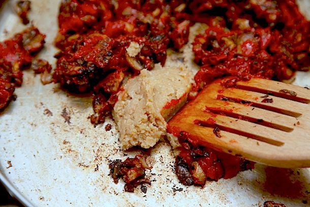 A spoonful of white miso is added to the pan of browned mushrooms and tomato paste.