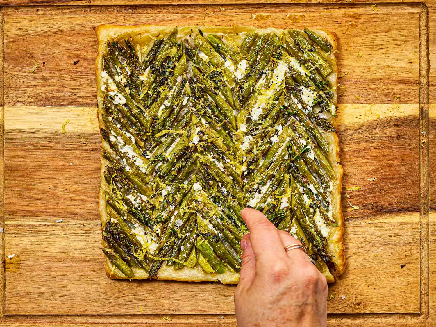 Overhead view of tart being sprinkled with lemon zest