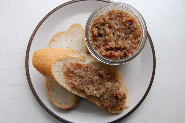 Overhead view of a canning jar of bacon-bourbon jam, served on a plae with two slices of baugette.