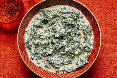 A bowl of creamed kale on a red tablecloth