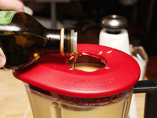Olive oil is added to a blender as the soup is puréed.