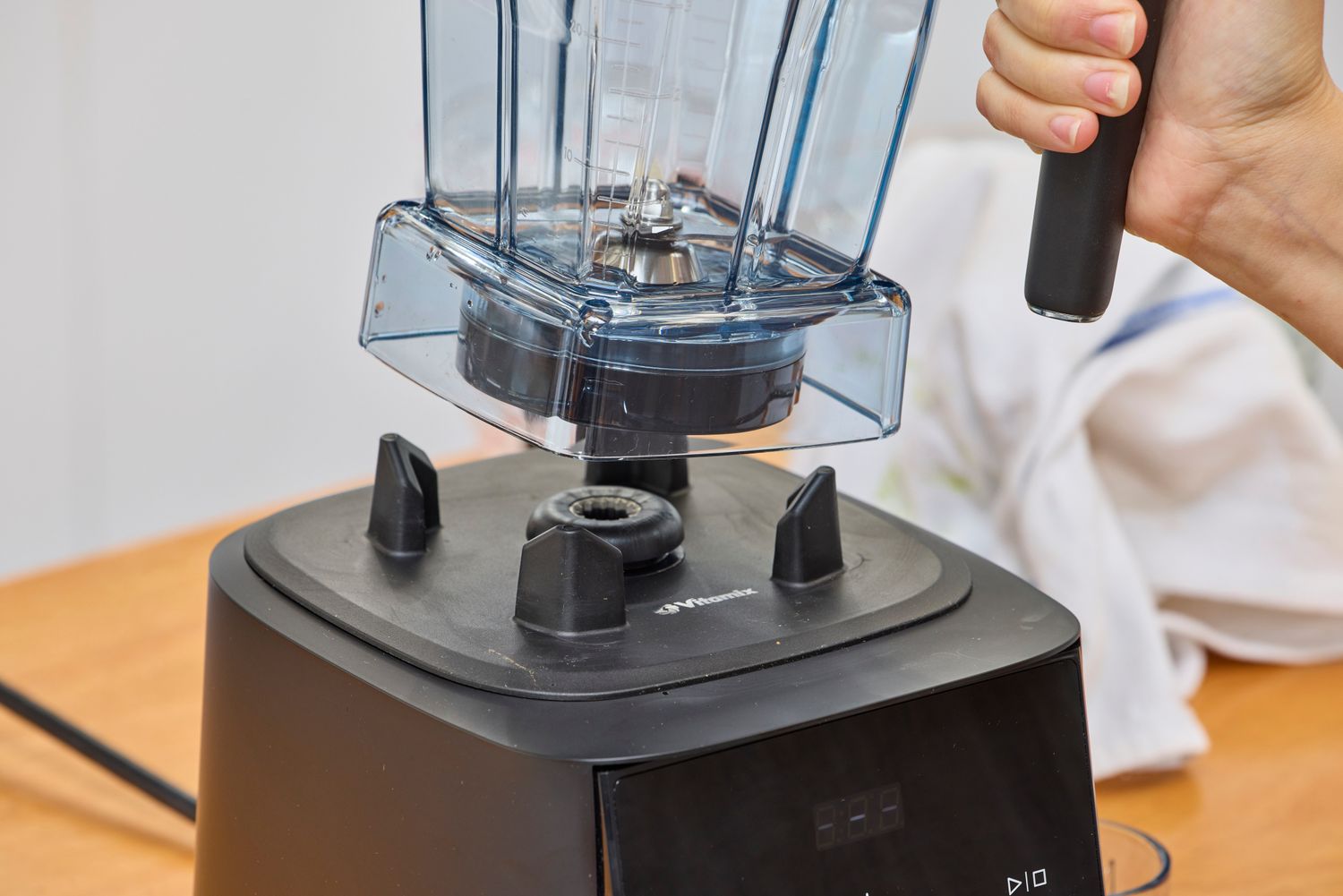 A hand lifting the Vitamix Ascent X2 jar from its base