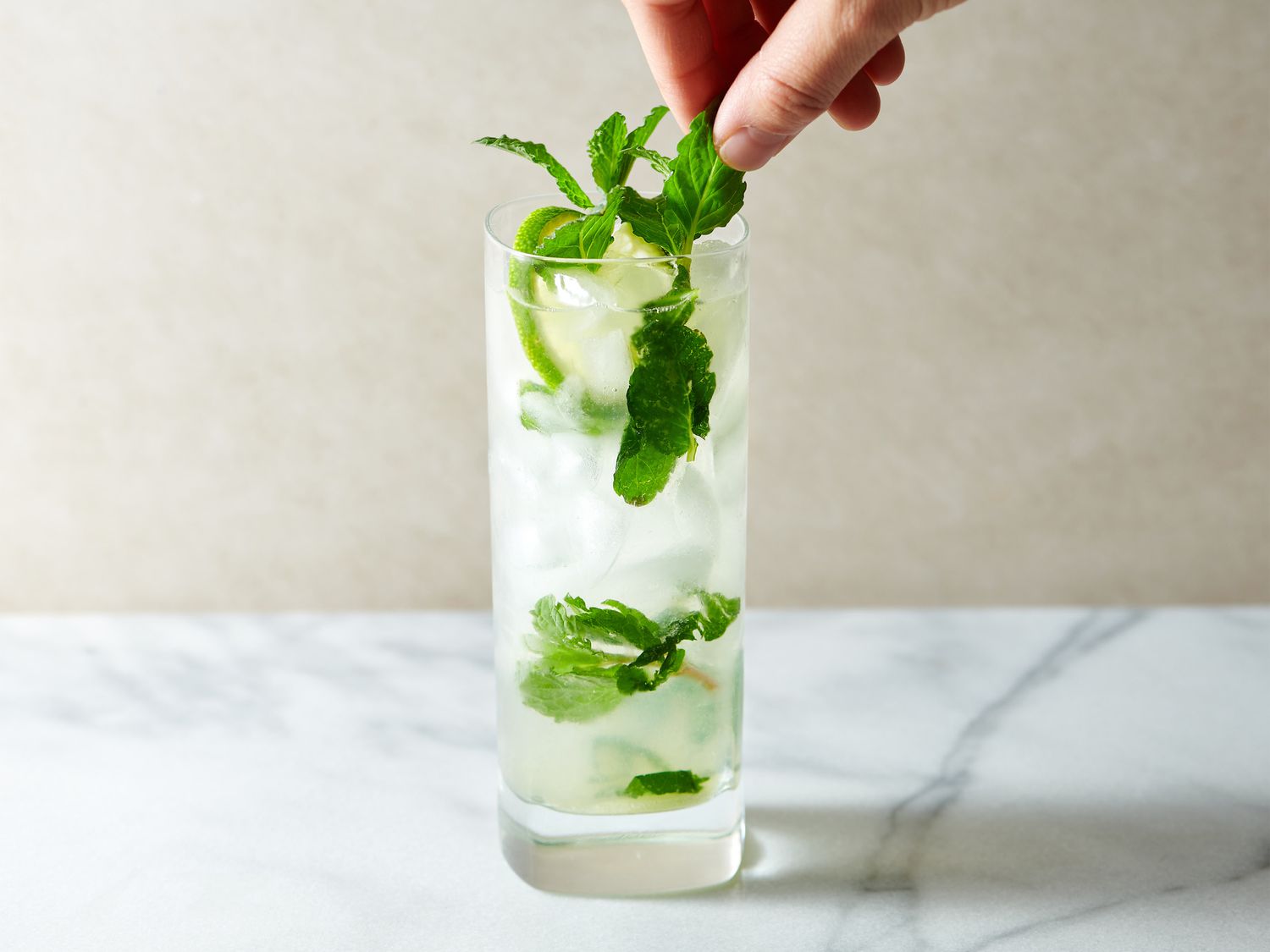 Drink topped with club soda, with mint sprigs and a lime twist added for garnish
