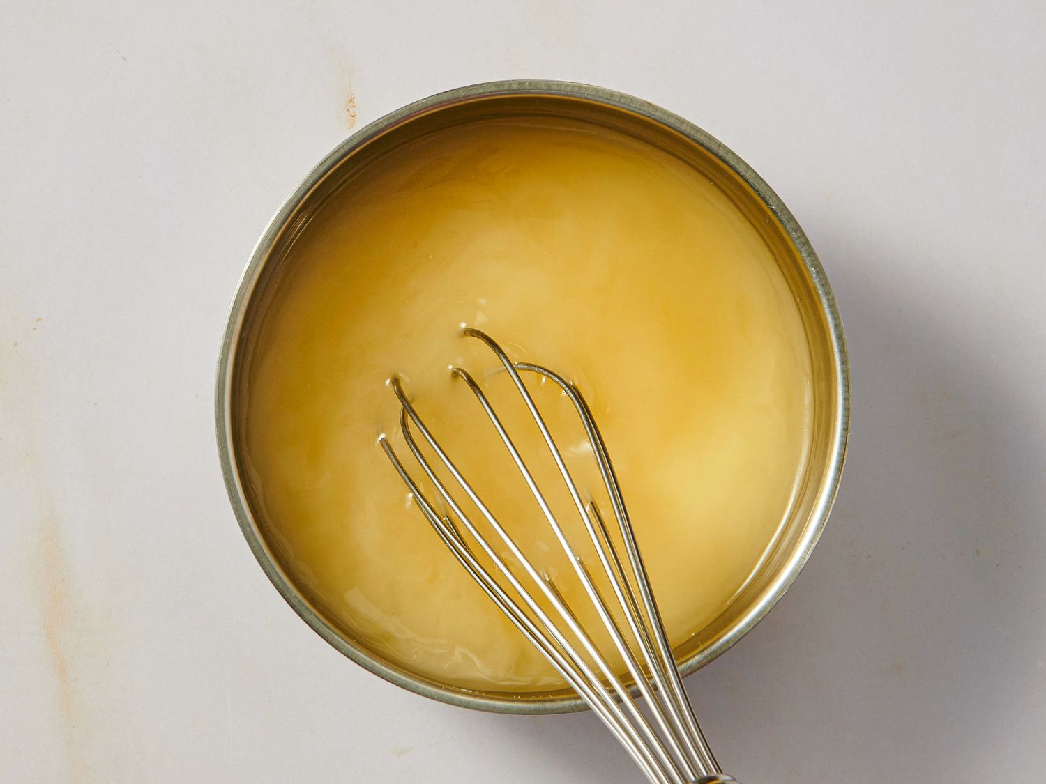 A whisk in a bowl of sauce or mixture likely part of a cooking process