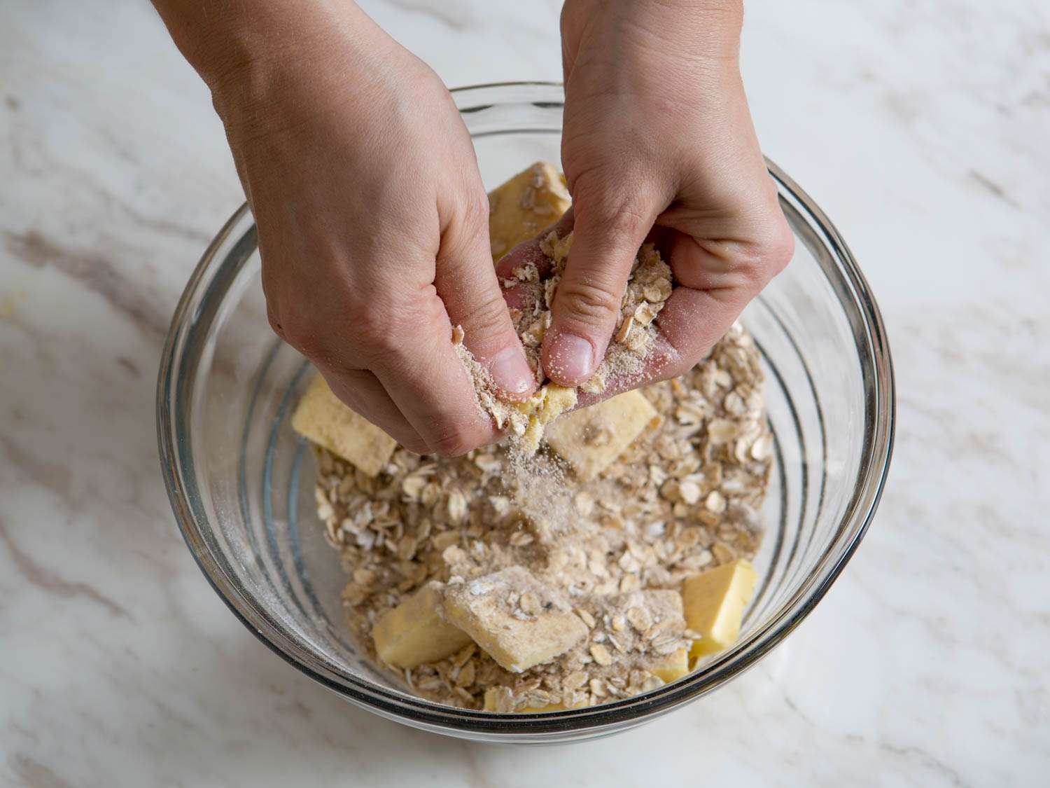 Smashing butter into dry ingredients by hand to form streusel.
