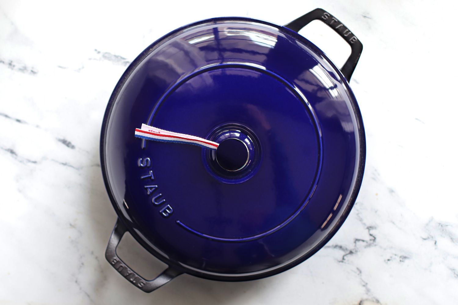 A blue Staub Cast Iron Braiser on a marble surface.