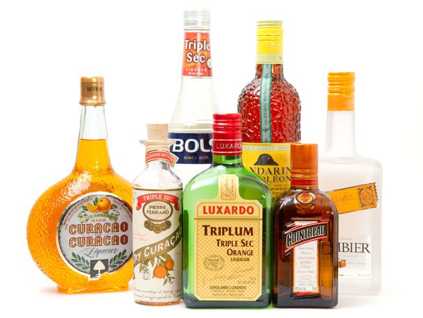 Seven different brands and styles of orange liqueur on a white surface