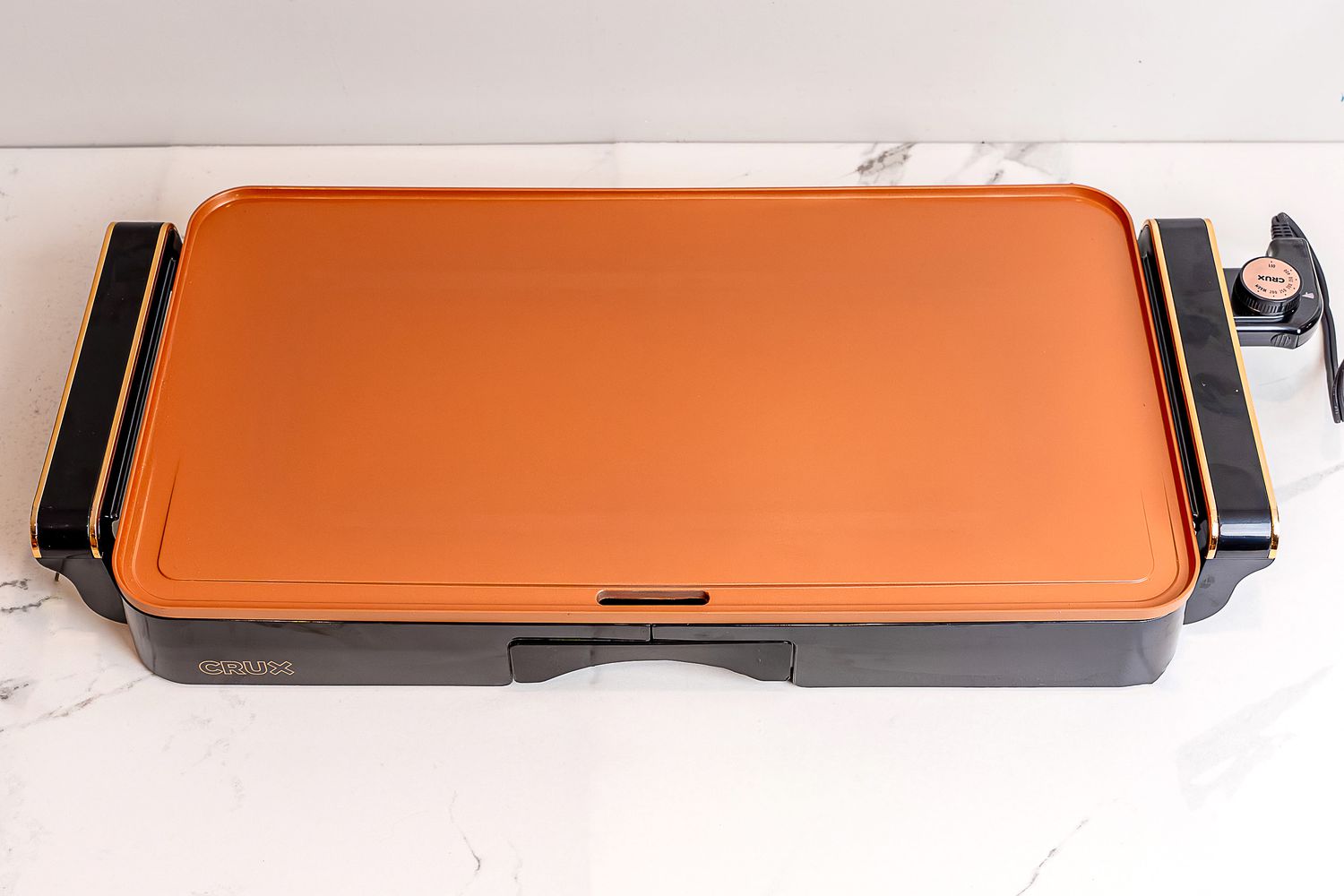 The Crux electric griddle on a white marble countertop