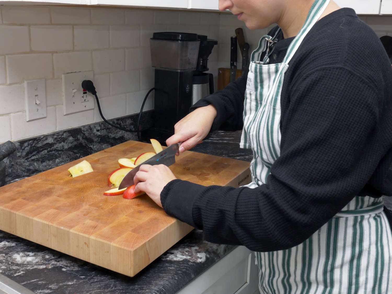 a person wearing the williams sonoma apron and chopping apples