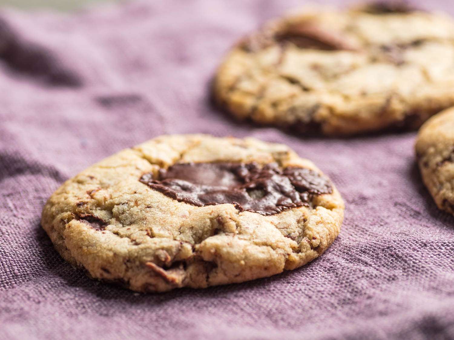 Close-up of chocolate chip cookies on a purple cloth.