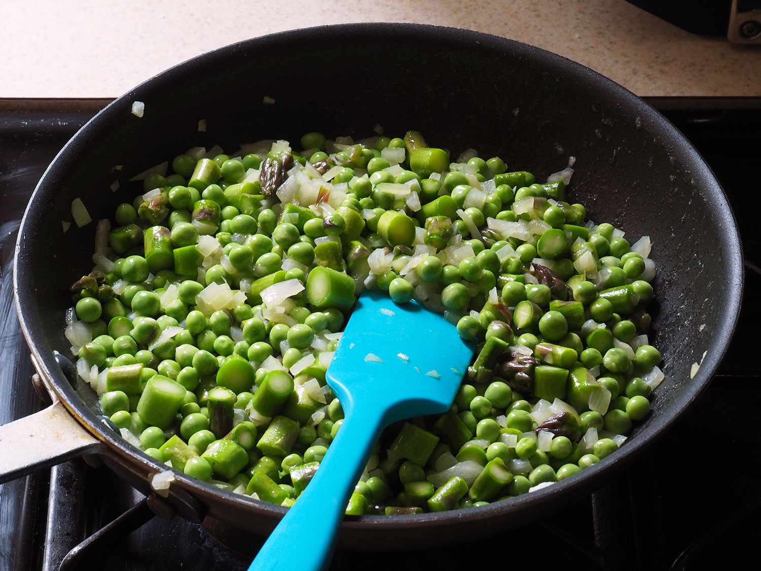 Peas and sliced asparagus are added to the skillet.