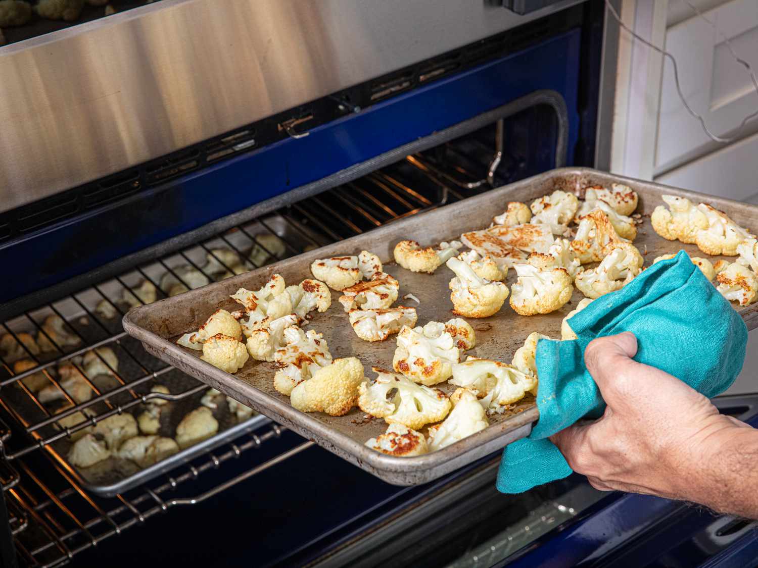 Overhead view of adding cauliflower to the oven