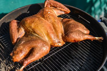 A spatchcocked turkey cooking on a grill. 