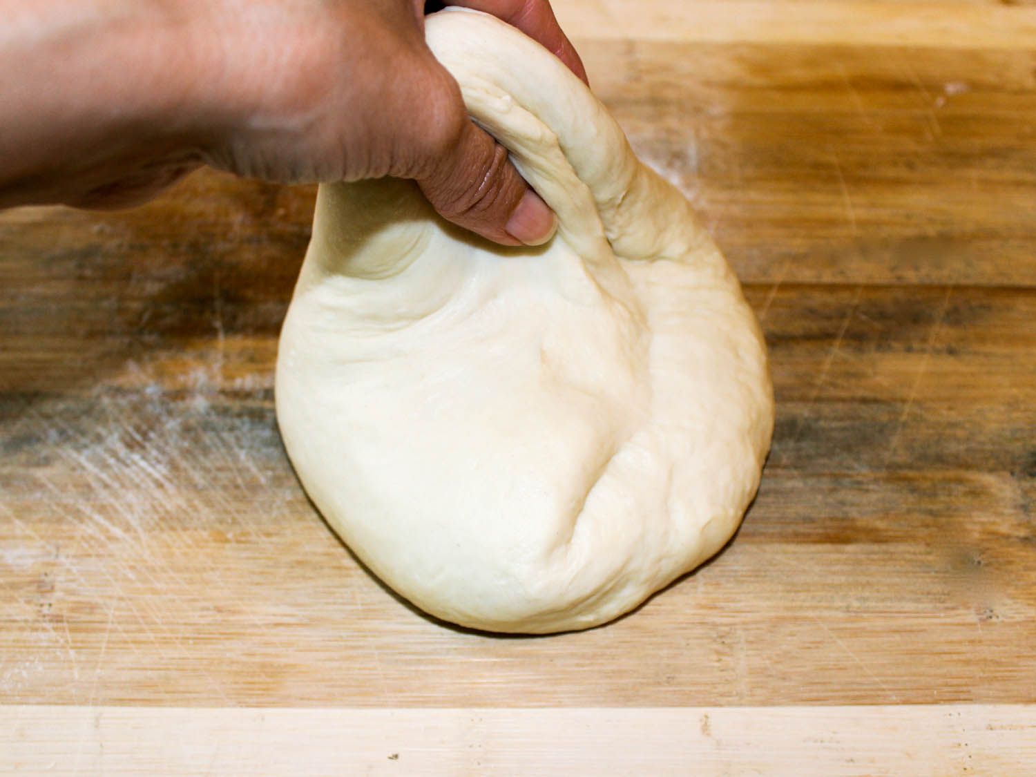 One portion of the dough is raised and stretched so that it can be folded on the rest of the dough.