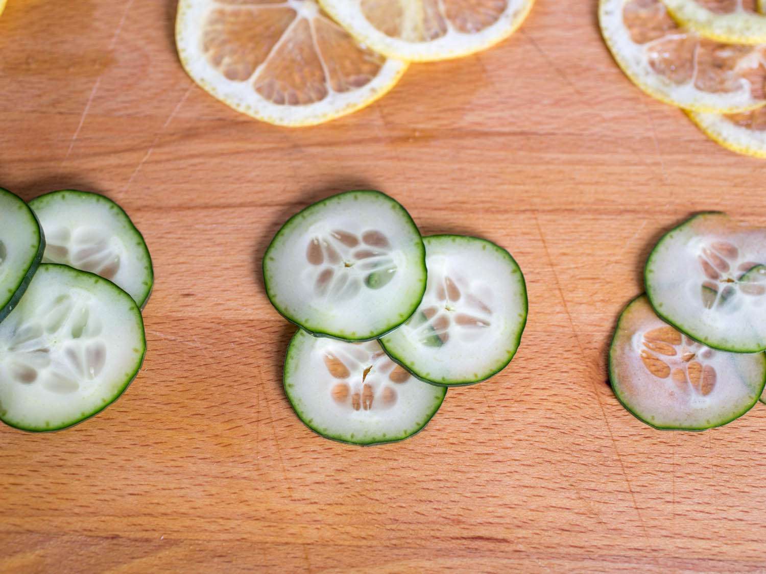 Close-up of cucumber slices cut in three different thicknesses on a wood surface