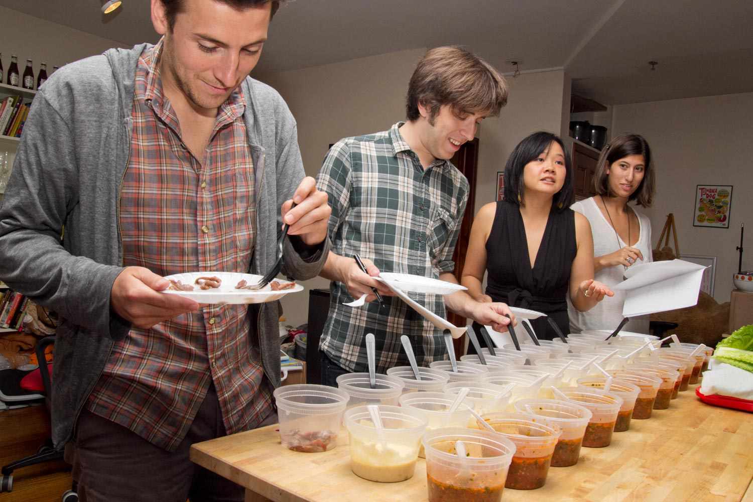 A group of people tasting anchovies in a kitchen
