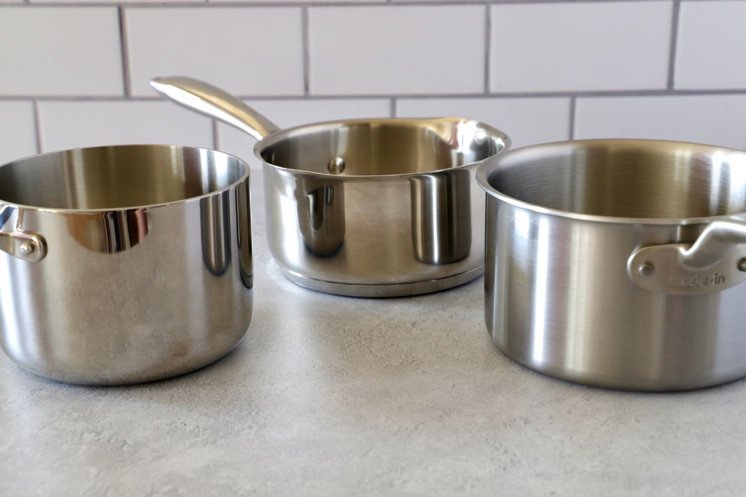 three saucepans on a grey surface