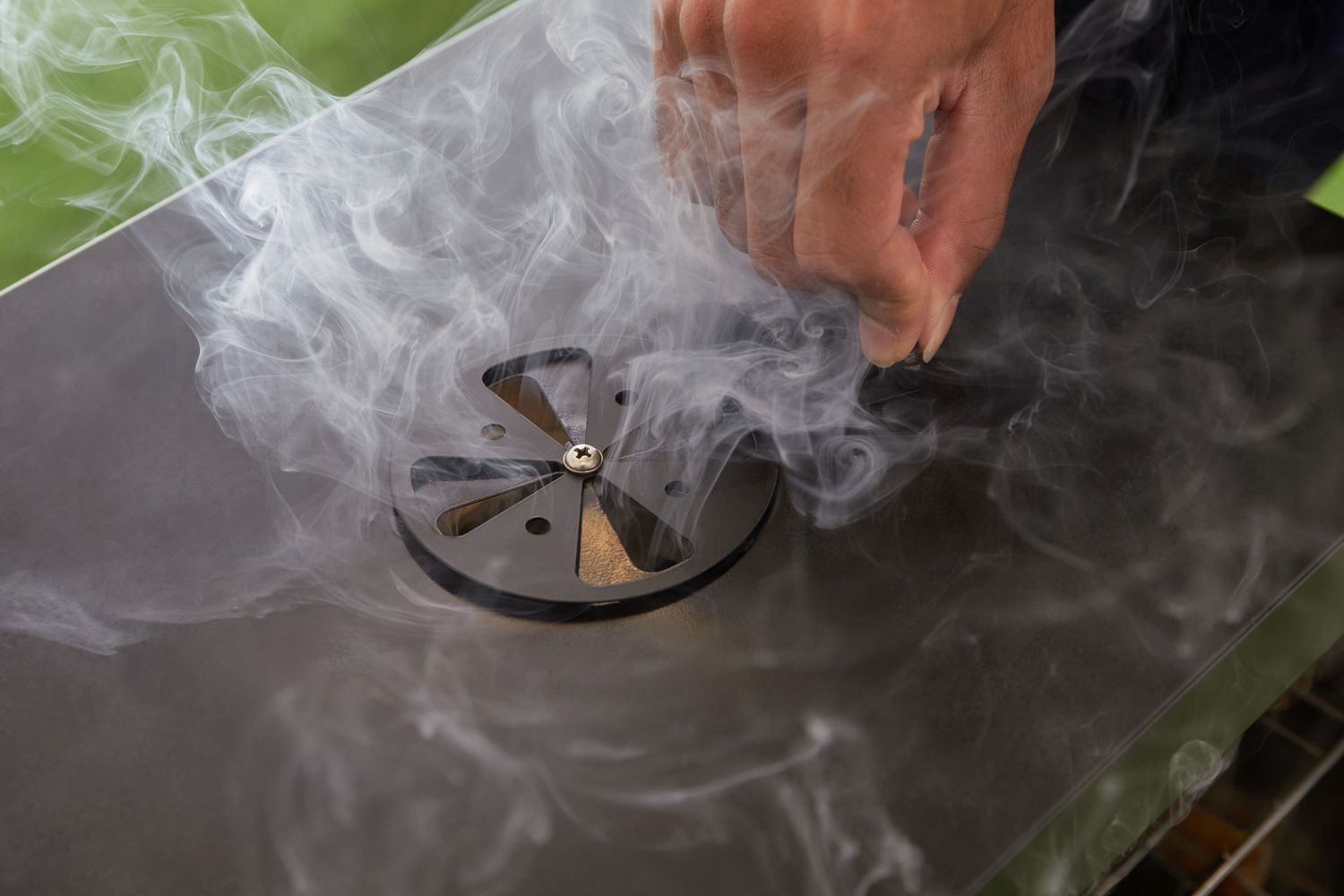 A person adjusting the damper on an electric smoker.