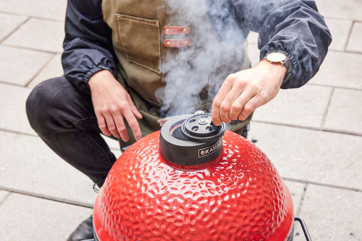 A person opens a smoke valve on the top of the Kamado Joe KJ13RH 13.5 inch Joe Jr. Charcoal Grill