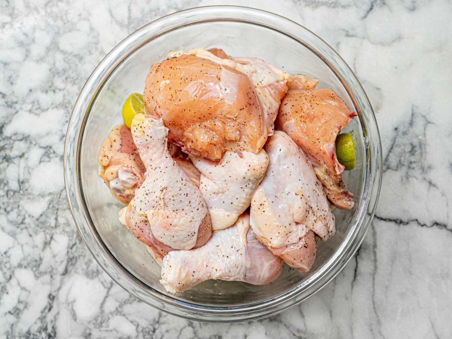 Chicken in a bowl with limes and seasoning