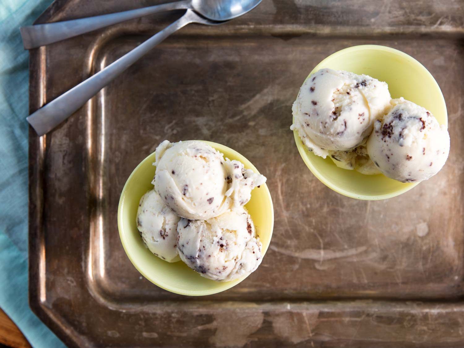 Overhead view of stracciatella gelato served in two pale yellow bowls.