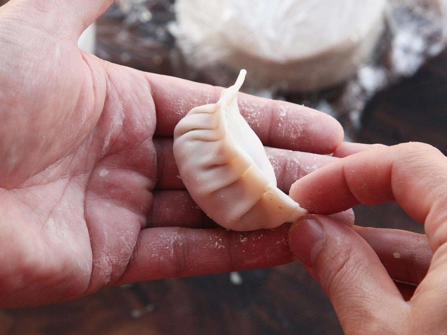 Plumping and shaping a newly formed gyoza in the palm of the hand. 