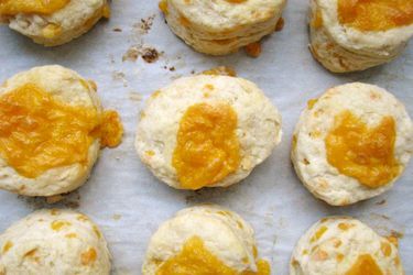 Overhead view of cheese buns on a parchment-lined baking sheet, fresh from the oven.