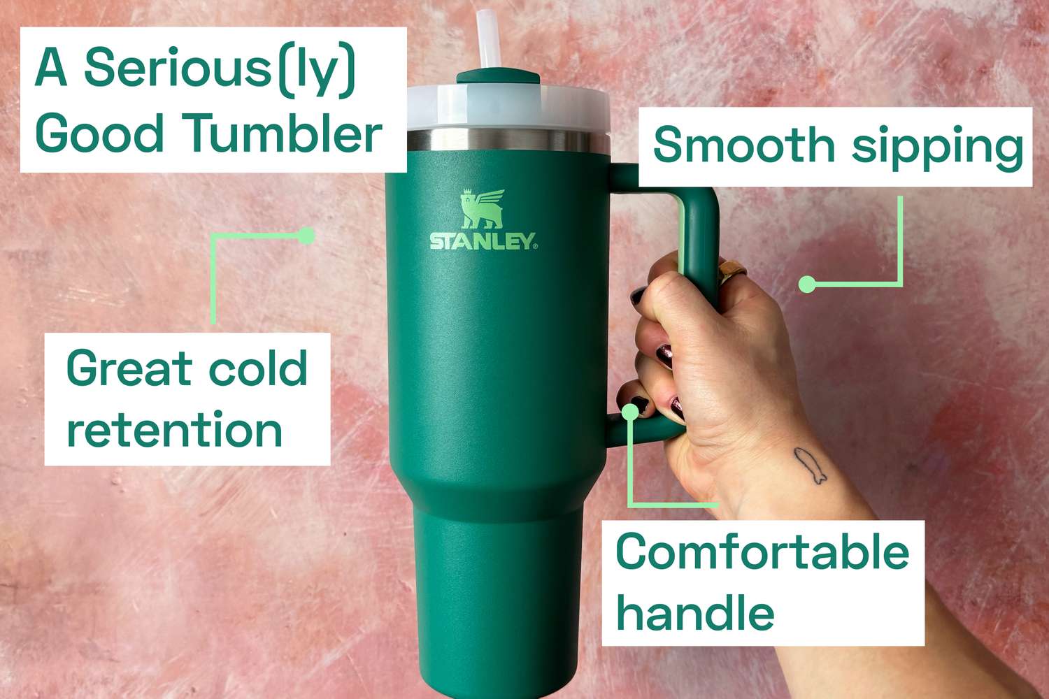 A person holding onto a Stanley tumbler via its handle.